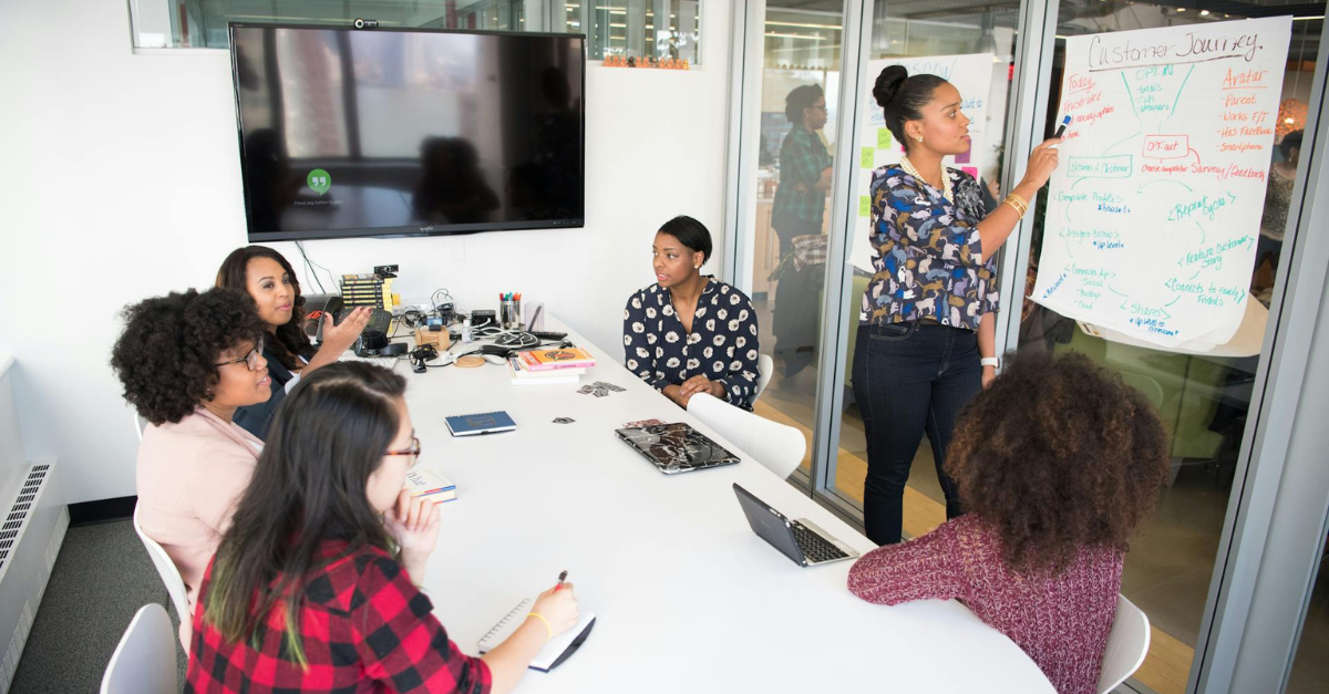 mulheres diversas conversando ao redor de uma mesa de escritório