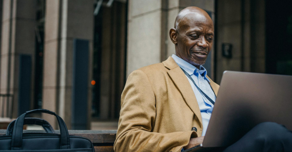 homem negro sentado e olhando para notebook cinza