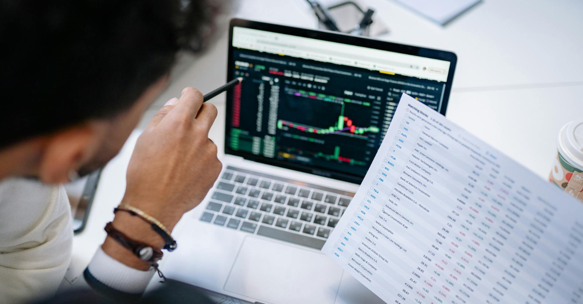 homem olhando para tela de computador com gráficos e números