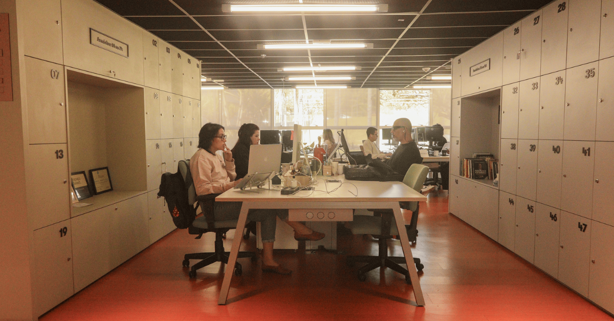 pessoas trabalhando em mesa compartilhada no coworking Impact Hub Brasília